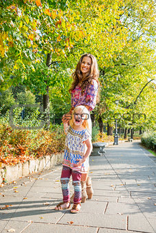 Portrait of happy mother and baby girl walking in city park