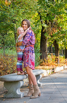 Happy mother and baby girl hugging in city park