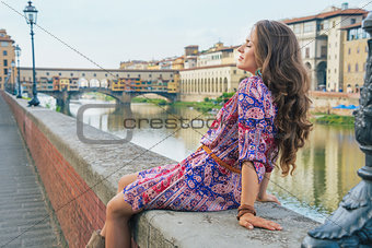 Relaxed young woman sitting near ponte vecchio in florence, ital