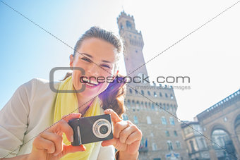 Happy young woman with photo camera in front of palazzo vecchio 