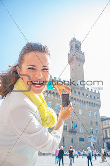 Happy young woman taking photo of palazzo vecchio in florence, i