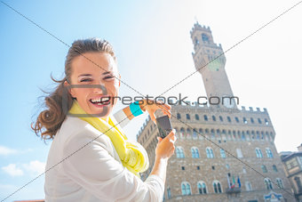 Happy young woman taking photo of palazzo vecchio in florence, i
