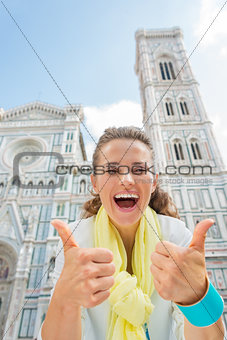Happy young woman showing thumbs up in front of duomo in florenc