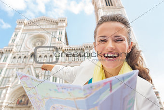 Happy young woman with map pointing on duomo in florence, italy