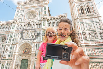 Smiling mother and baby girl making selfie in front of duomo in 