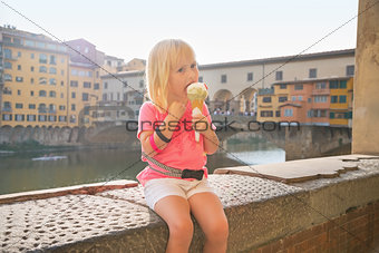 Portrait of happy baby girl eating ice cream near ponte vecchio 