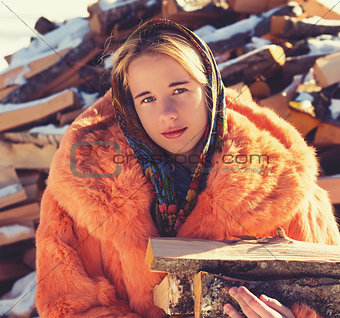 Teenage girl in red fur coat with firewood.