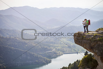 Happy young couple with little son standing on cliff over river
