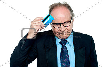 Businessman scratching his forehead with plastic card