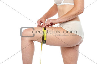 Fit woman in lingeries measuring her thighs