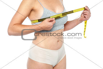 Lingerie clad measuring her breast