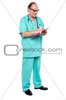 Mature medical practitioner writing case history of a patient
