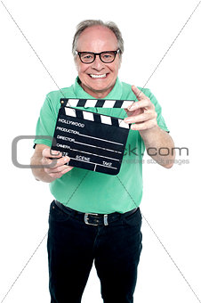 Bespectacled elderly man holding a clapperboard