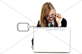 Girl adjusting her spectacles while working on laptop