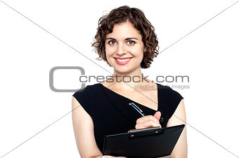 Charming woman writing notes on clipboard