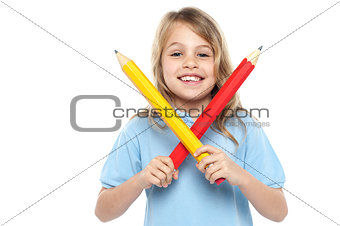 Young girl holding big red and yellow pencils