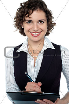 Happy businesswoman writing on clipboard