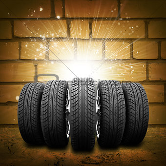 Car wheels. Background is brick wall, concrete floor and light at center