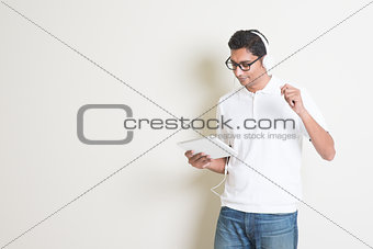 Indian guy playing music with tablet and dancing