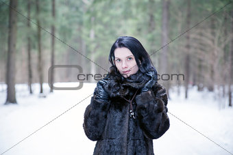 Girl wearing a fur coat in winter forest