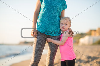Baby girl hugging mother on beach in the evening