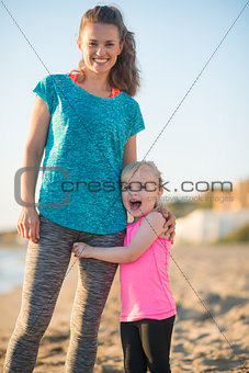 Happy baby girl hugging mother on beach in the evening