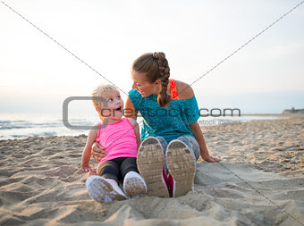 Portrait of fitness mother and surprised baby girl sitting on be