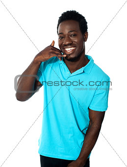 Smiling young man showing calling gesture