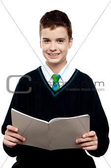 Charming schoolboy holding workbook