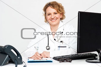 Smiling middle aged female doctor sitting in clinic