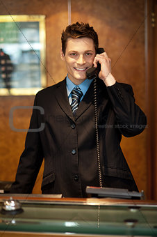 Cheerful front desk executive attending phone call