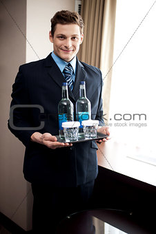 Male butler holding fresh beverages for customers