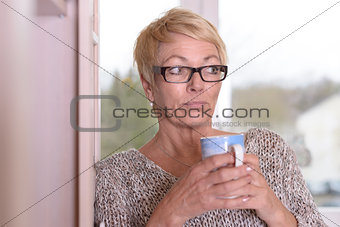 Serious Blond Woman with Glasses Holding a Cup