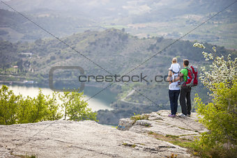 Young couple with toddler boy standing on cliff and enjoying view below
