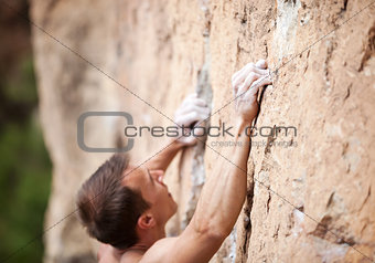 Cropped view of male rock climber on cliff, hands in focus