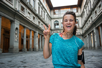 Happy fitness woman showing victory gesture near uffizi gallery 