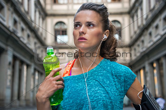 Thoughtful fitness woman with bottle of water near uffizi galler