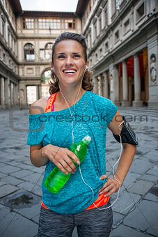 Happy fitness woman with bottle of water near uffizi gallery in 