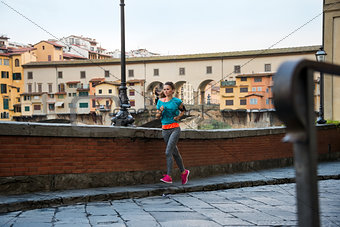 Fitness woman jogging near ponte vecchio in florence, italy