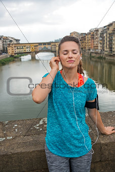 Fitness woman listening music in front of ponte vecchio in flore
