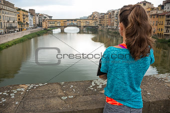 Fitness woman looking on ponte vecchio in florence, italy. rear 