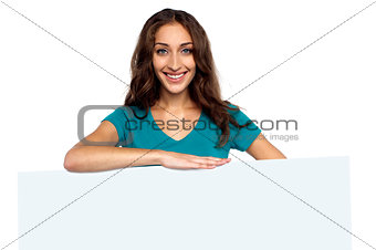 Young casual woman behind blank ad board