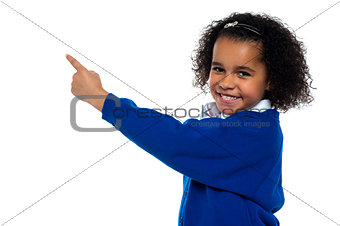 Adorable African kid pointing at copy space area