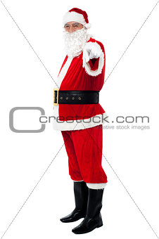 Senior man in Santa costume pointing at you