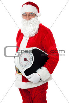 Aged male Santa holding weighing scale