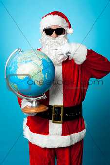 Stylish Santa in dark shades pointing at the globe
