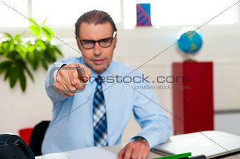 Serious manager pointing at you from his work desk