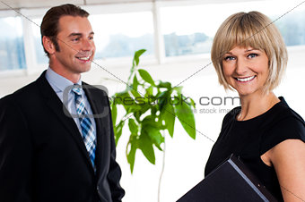 Handsome boss passing by smiling female colleague