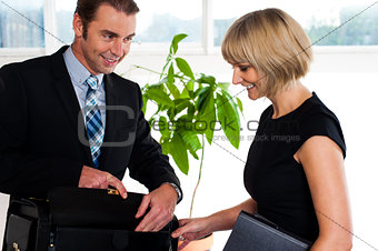 Boss opening his briefcase in front of secretary