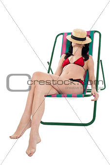 Slim woman relaxing. Face covered with hat.